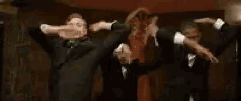 a group of men in tuxedos are dancing together .