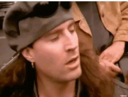 a close up of a man wearing a hat and earrings