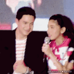 a man and a woman are standing next to each other and the woman is holding a microphone and the man is smiling