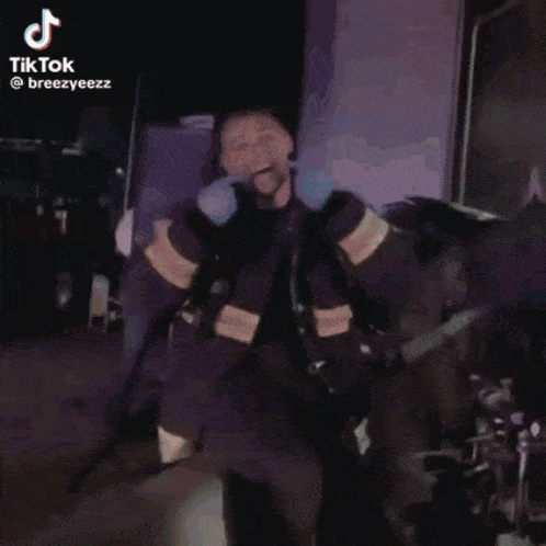 a man in a firefighter 's uniform is dancing in front of a blue wall .