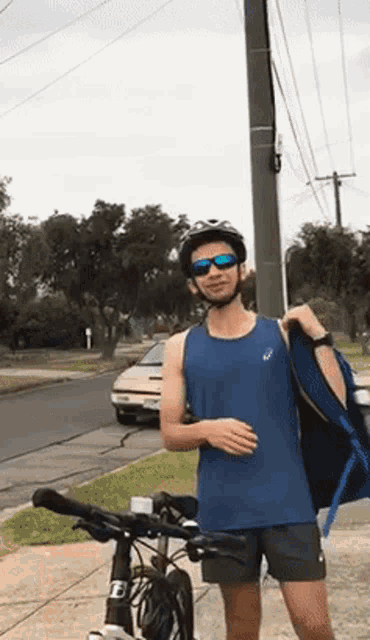 a man wearing a helmet and sunglasses standing next to a bike