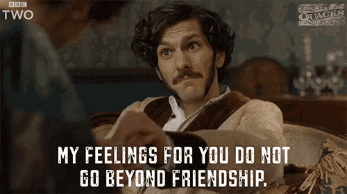a man with a mustache is sitting on a couch and talking to another man .