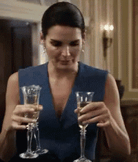 a woman in a blue dress is holding two glasses of champagne .