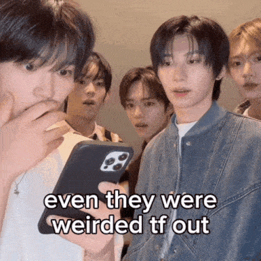 a group of young men are looking at a cell phone and one of them says even they were weirded tf out