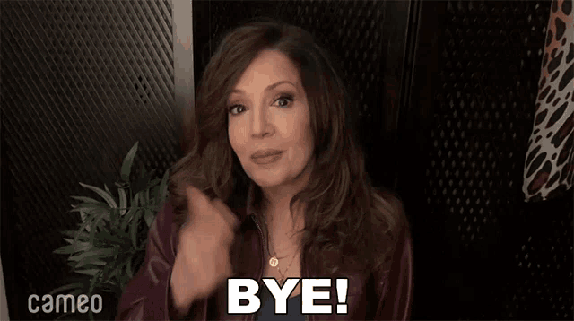 a woman says bye in front of a cameo sign