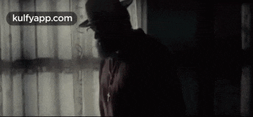 a man in a cowboy hat is standing in front of a window with the website kulfyapp.com in the corner .