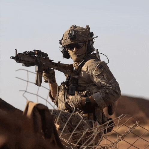 a soldier with a helmet and sunglasses holds a gun
