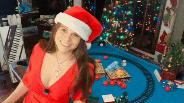 a woman in a santa hat stands in front of a pool table