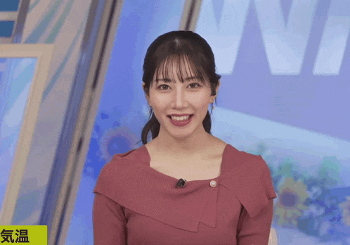 a woman in a pink dress is smiling in front of a sign that says " nn "