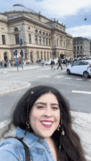 a woman is smiling in front of a large building