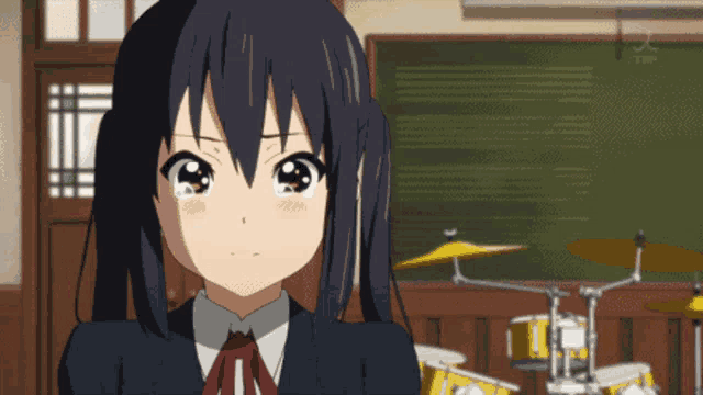 a girl with black hair is standing in front of drums