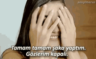 a woman is covering her face with her hands and smiling in a foreign language .