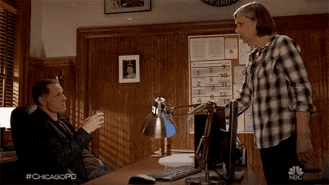 a man sits at a desk while a woman stands in front of a computer with the hashtag #chicagopd on the screen