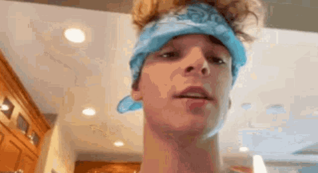 a young man wearing a blue bandana on his head .