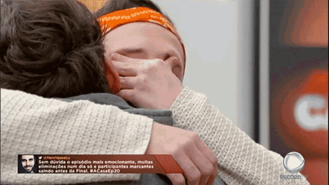 a woman with a bandana on her head is hugging a man who is covering her face