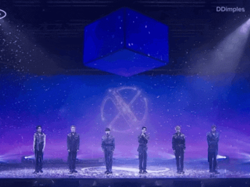 a group of men standing on a stage with a blue cube in the background and the word dimples on the bottom