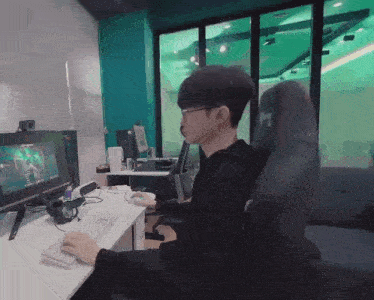 a man is sitting at a desk with a keyboard and a monitor behind him
