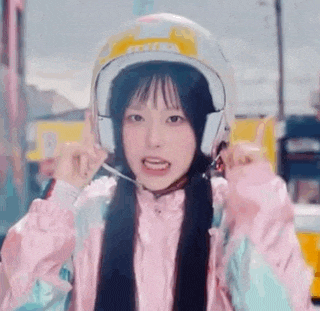 a young girl wearing a helmet and headphones is giving a thumbs up .