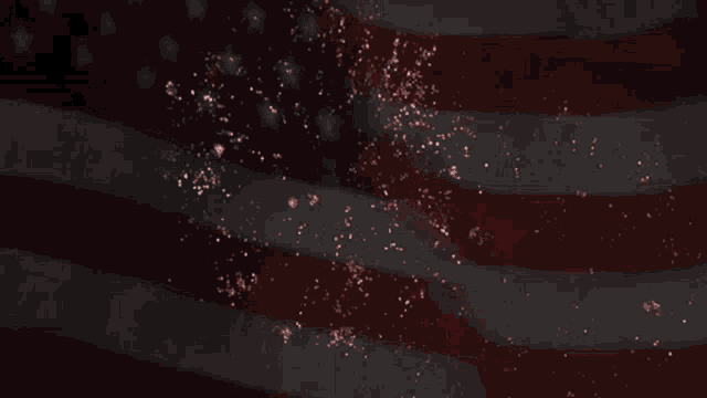 fireworks are exploding in the night sky in front of an american flag .