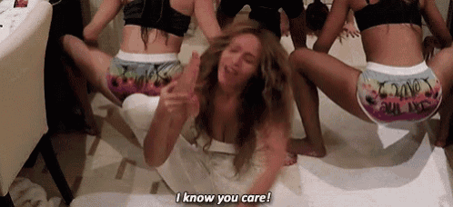 a group of women are dancing on a bed and one of them is giving the middle finger .