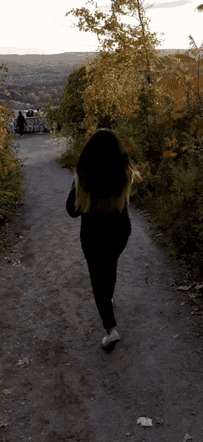 a woman walking down a path with a view of a city