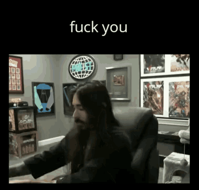 a man with long hair and a beard is sitting in a chair with the words " fuck you " on the bottom
