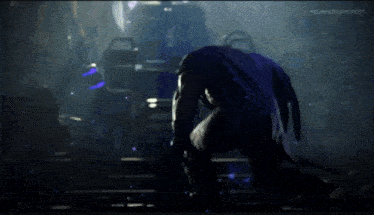 a man in a purple cape is kneeling down in a dark room at the summer gamefest