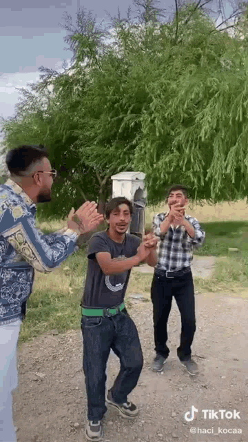 a group of young men are dancing in front of a tree in a tiktok video