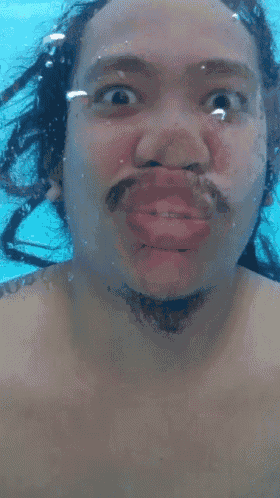 a man with dreadlocks and a nose ring is swimming underwater