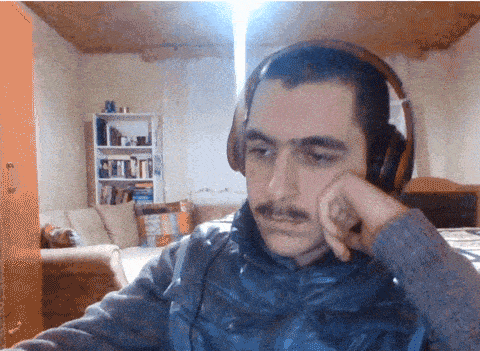 a man with a mustache wearing headphones looks tired