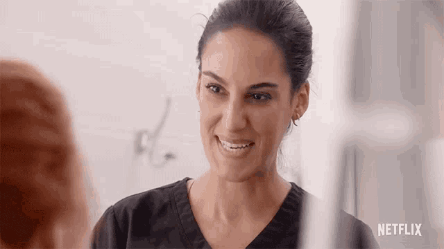 a woman in a black scrub top is smiling at another woman .