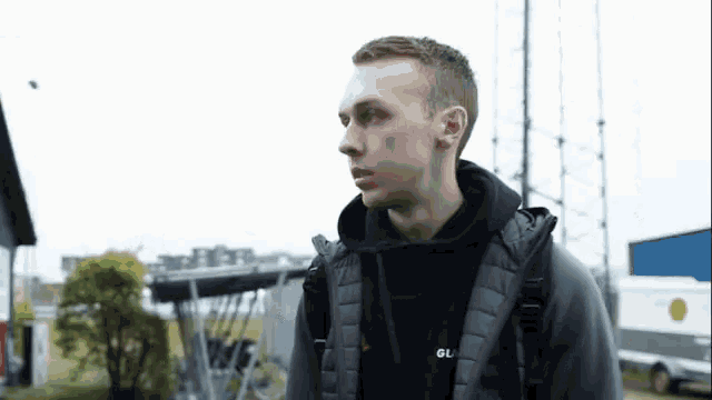 a man wearing a black hoodie and a grey jacket with the word gu on it