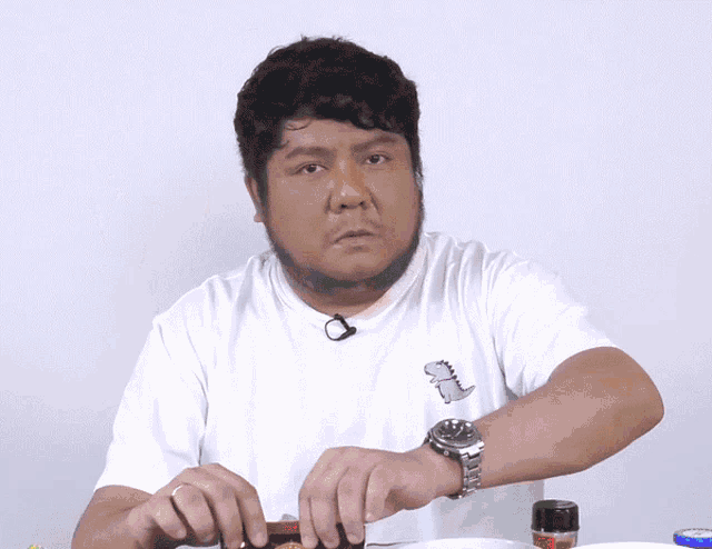 a man wearing a watch and a white shirt with a dinosaur on the front