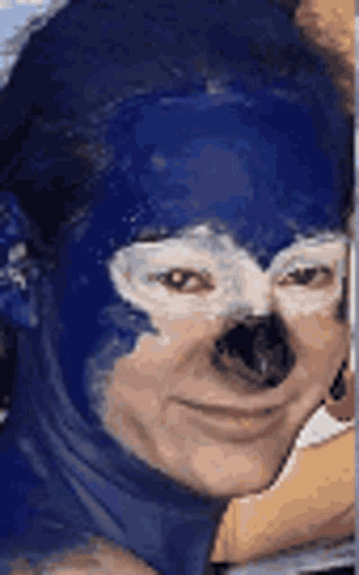 a person with their face painted like sonic the hedgehog is smiling .