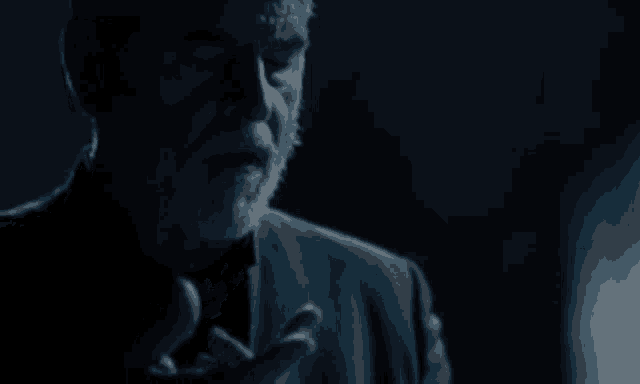 a close up of a man 's face with a beard in a dark room .