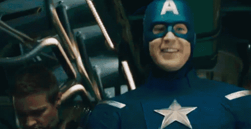 a man in a captain america costume is smiling and giving a thumbs up .