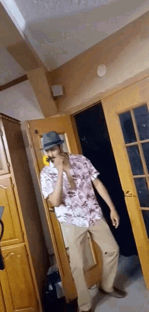 a man wearing a hat and a hawaiian shirt is standing in a room .