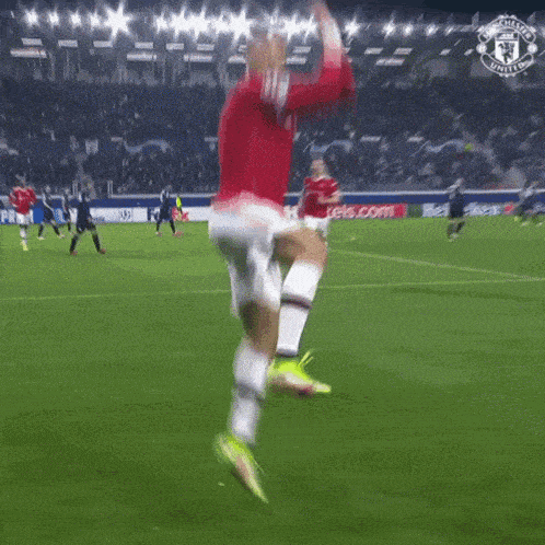 a man in a red jersey with the number 7 on it jumps in the air on a soccer field