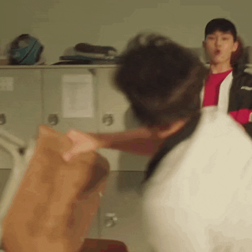 two men are fighting in a locker room and one of them is pointing at the other .
