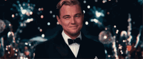 a man in a tuxedo and bow tie is smiling in front of a crowd