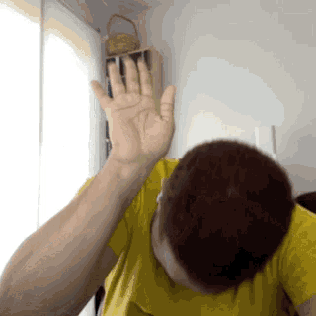 a man in a yellow shirt holds his hand up in the air