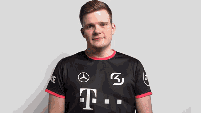 a man wearing a black t-mobile shirt looks down with his eyes closed
