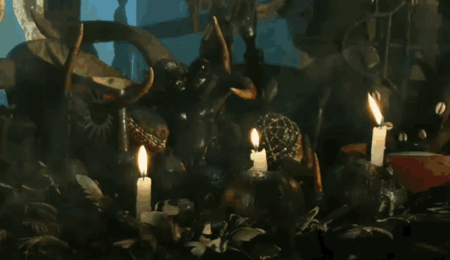 candles are lit in front of a statue of a devil