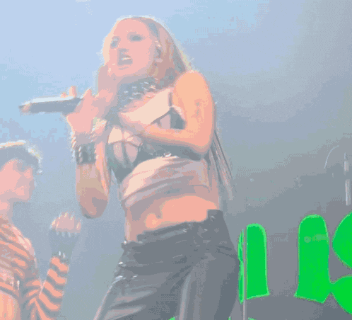 a woman with long red hair is dancing in front of a green sign