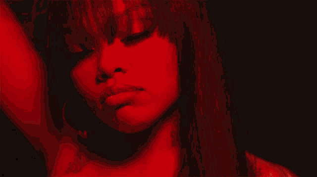 a close up of a woman 's face with red light behind her