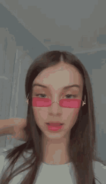 a girl wearing pink sunglasses is making a face .