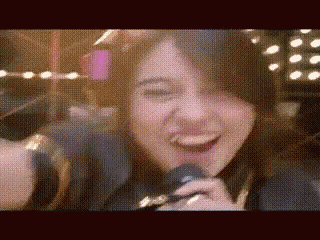 a woman is singing into a microphone and smiling .