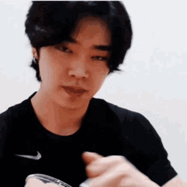 a young man in a black shirt is holding a spoon in his hand and looking at the camera .