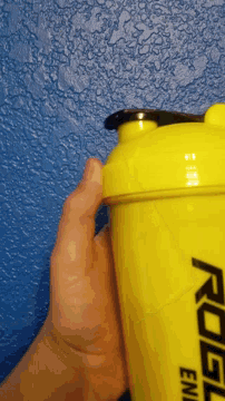 a person holding a yellow bottle that says rogl energy
