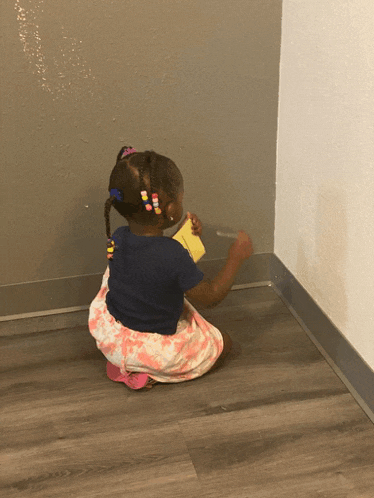 a little girl is kneeling down on the floor holding a yellow sticky note